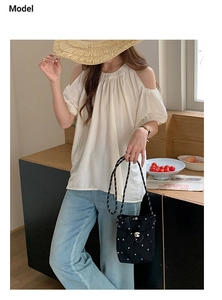 Détail mode d'un sac seau noir à pois porté avec une tenue d'été décontractée