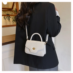 Detail of elegant cream faux leather handbag with gold metal lock on black suit