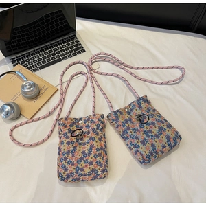 Detail of floral canvas crossbody bag with woven rope strap and silver snap button closure