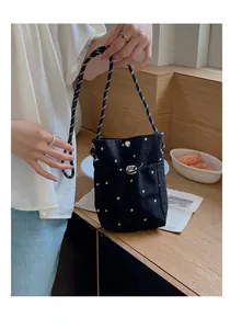 Détail du sac seau en toile noire à fleurs avec bandoulière tressée et cordon de serrage
