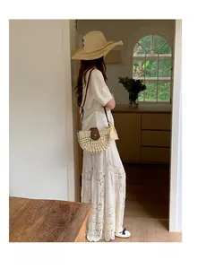 Detail of hand-woven straw crossbody bag styled with a summer outfit and sun hat