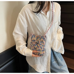 Detail of floral crossbody phone bag with drawstring and pink woven strap on model