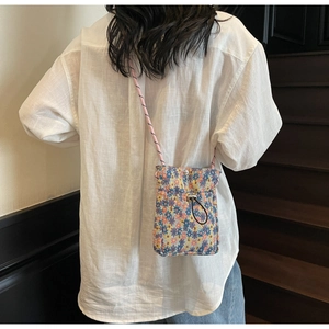 Detail of floral crossbody phone bag with drawstring and woven shoulder strap