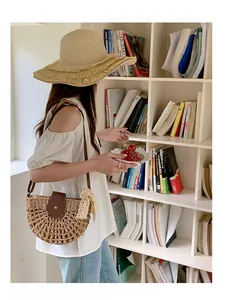Detail of straw woven crescent bag with brown leather flap and matching fringe sun hat