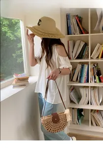 Summer vacation outfit with straw handbag, fringed sun hat, and white off-shoulder top