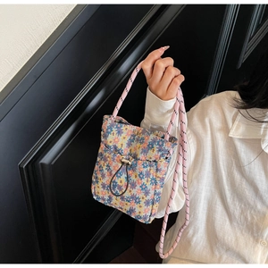 Close-up of floral knit crossbody bag with drawstring pocket and woven shoulder strap