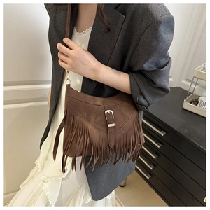 Dettaglio della borsa a mezzaluna in camoscio marrone con lunghe frange e fibbia boho