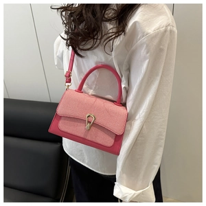 Detailed shot of a pink woven fabric flap handbag with metallic gold-tone clasp and strap