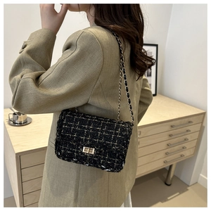 Close-up of black and gold tweed chain bag worn with a stylish blazer in a home setting
