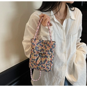 Detail of floral drawstring crossbody phone bag with patterned woven handle and outer pocket