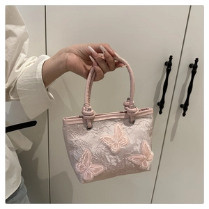 Detail of pink lace bucket bag featuring 3D butterfly embroidery and woven handle
