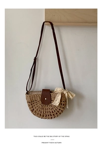 Detail of woven straw bag with brown leather flap, magnetic buckle, and white lace bow