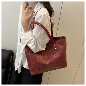 Detail of red woven texture tote bag featuring silver rivets and slim shoulder straps