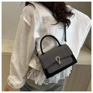 Detail of vintage grey fabric and black leather crossbody bag with golden horseshoe lock