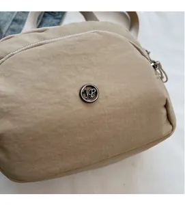 Detail of nylon bag with metallic JP logo and smooth rippled fabric texture