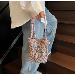 Close-up of floral canvas mini bag with pink woven handles and metal drawstring lock