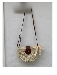Detail of hollow woven straw bag with leather flap and lace bow on textured wall