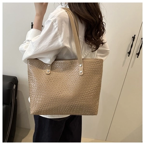 Detail of beige woven texture tote bag with silver rivets and long shoulder straps