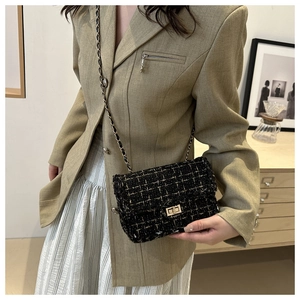 Detailed view of black tweed chain bag with gold thread accents on a cross-body strap
