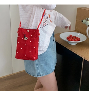 Détail du petit sac à téléphone rouge en toile avec motif floral et cordon serrage