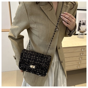 Detail of tweed crossbody bag with gold chain strap and metal lock shown on model