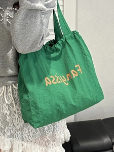 Large green nylon tote bag with orange lettering and drawstring detail for women