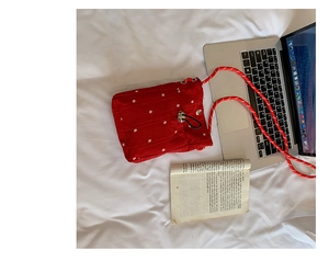 Détail du sac matelassé rouge avec motif floral blanc et bandoulière en corde tressée