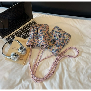 Detail view of floral crossbody phone bags with pink braided rope and drawstring closure