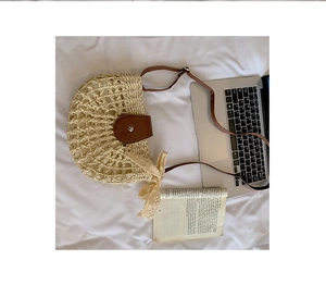 Detail of woven straw crossbody bag with brown leather flap and side lace bow decoration