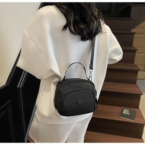 Detailed view of a black nylon crossbody bag worn by a model in a casual sporty outfit