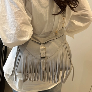 Borsa a mezzaluna in camoscio grigio con frange lunghe e dettagli dorati su modella