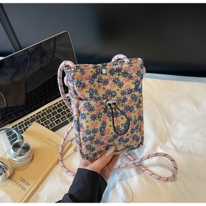 Detail of floral jacquard fabric on a crossbody phone bag with drawstring front pocket