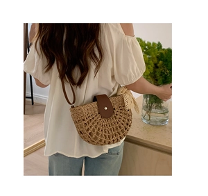 Detailed shot of hollowed straw bag with brown leather flap and beige lace bow decoration