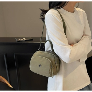 Olive green nylon tote bag with multi-zipper compartments and adjustable strap