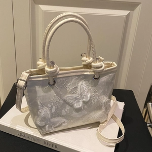 Ivory lace bucket bag with 3D butterfly embroidery and dual handles in soft warm lighting