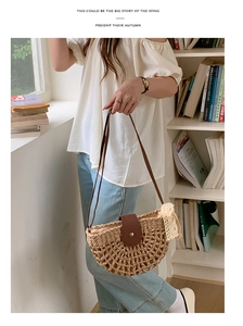 Detail of woven straw shoulder bag featuring white lace trim and brown leather strap