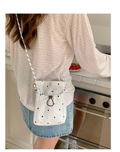 Détail du sac bandoulière en toile blanche à fleurs avec cordon et bandoulière noire