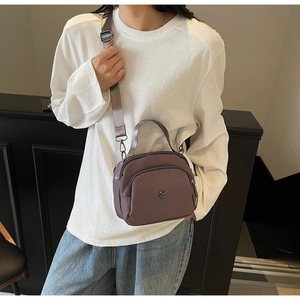 Detail of multi-layer zipper nylon shoulder bag in deep purple with adjustable strap