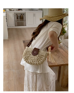 Detail of hollow woven straw bag featuring brown leather flap and delicate lace bow