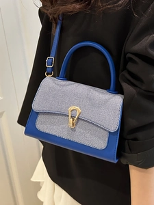 Blue veg-tan leather crossbody bag with striped fabric and horse-bit buckle on model