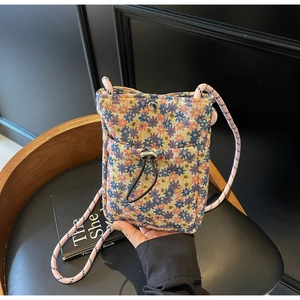 Detailed close-up of floral woven crossbody phone bag with drawstring front pocket