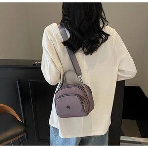 Mauve nylon shoulder bag with wide strap shown on model in a minimalist setting