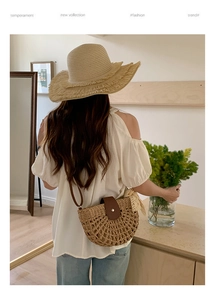 Detailed back view of a hollow woven straw shoulder bag with a brown leather flap and strap