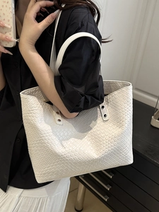 White large capacity woven tote bag with slim shoulder straps shown on shoulder