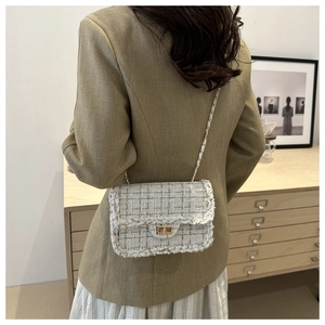 Detailed back view of a white tweed chain bag with gold woven patterns on a model
