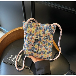 Detail of floral tapestry phone bag with drawstring pocket and woven rope shoulder strap