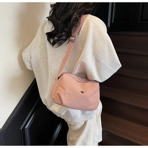 Detail of pink nylon crossbody bag with adjustable fabric strap and metallic buckle