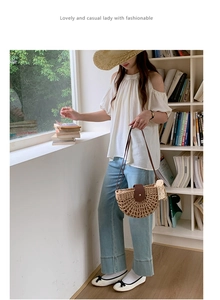 Detail of semi-circular woven straw bag featuring brown leather buckle and lace trim