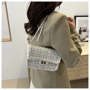 Detail of tweed crossbody bag with woven golden thread and metal chain strap