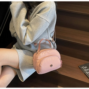 Pink nylon crossbody bag detail with multi-layer zipper pockets and adjustable strap